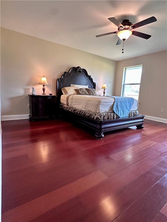 bedroom with ceiling fan, baseboards, and wood finished floors