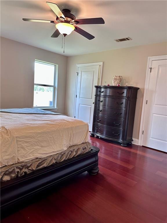 bedroom featuring dark wood finished floors, a ceiling fan, and visible vents