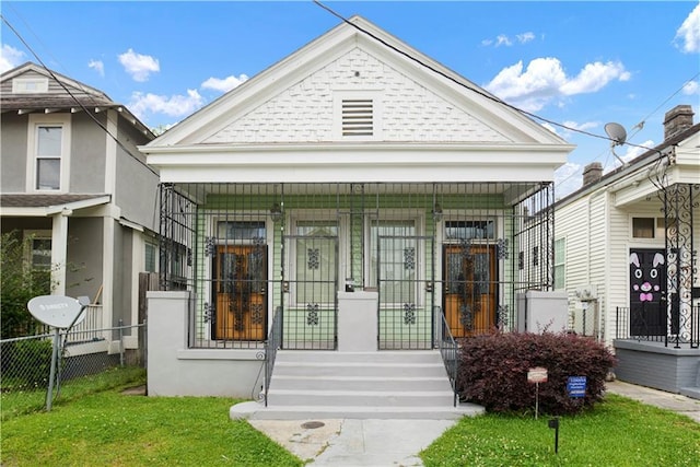 view of front of home featuring covered porch, fence, and a front lawn