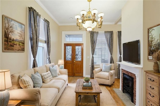 living room with crown molding, light wood finished floors, an inviting chandelier, and a fireplace with flush hearth