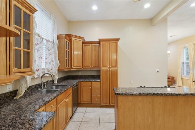 kitchen featuring dark stone countertops, brown cabinets, stainless steel dishwasher, and a sink