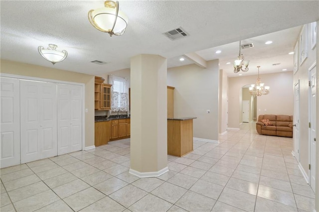 interior space with open shelves, dark countertops, visible vents, a notable chandelier, and light tile patterned flooring