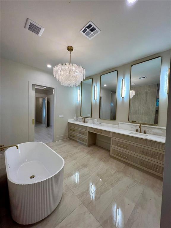 138 Wood Duck Dr, Belle Chasse, LA 70037 - bathroom featuring a freestanding bath, marble look tile flooring, double vanity, a chandelier, and recessed lighting