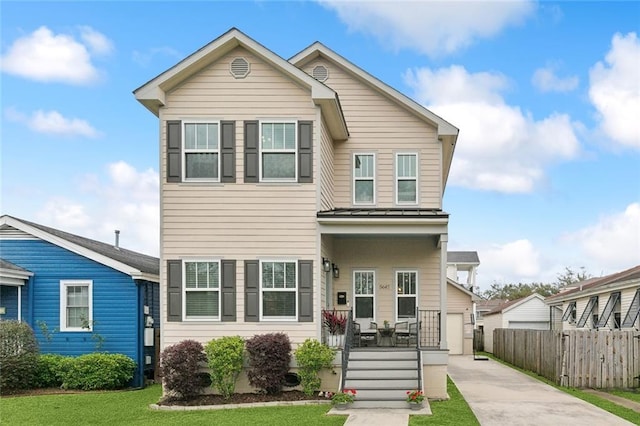 view of front facade featuring a porch, fence, concrete driveway, a front yard, and metal roof