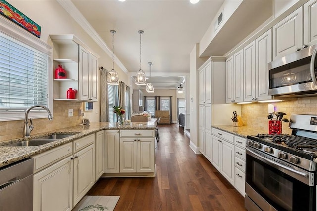 kitchen featuring ornamental molding, a ceiling fan, a sink, stainless steel appliances, and a peninsula