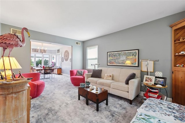 carpeted living room with visible vents, baseboards, and a notable chandelier