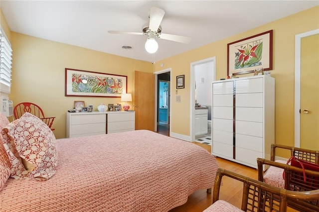 bedroom featuring visible vents, a ceiling fan, ensuite bath, light wood-style floors, and baseboards