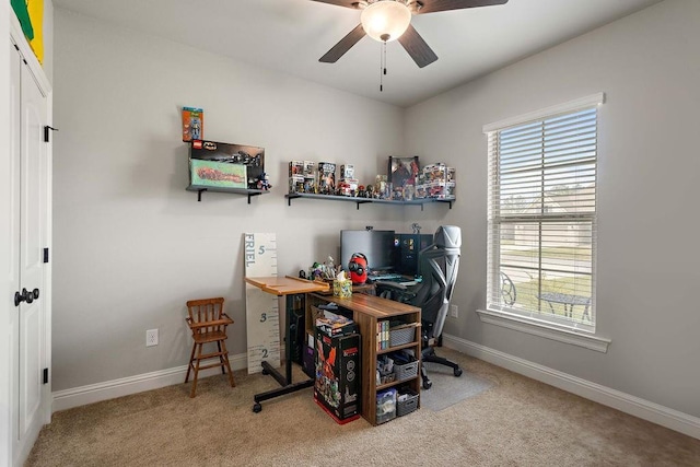 carpeted office space featuring baseboards and a ceiling fan