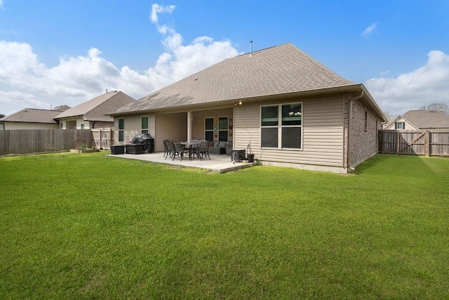 rear view of property featuring a lawn, roof with shingles, a fenced backyard, and a patio area