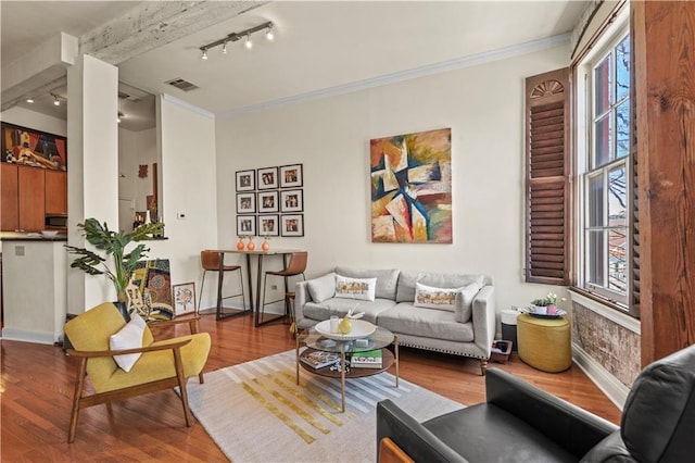 living room featuring wood finished floors, visible vents, baseboards, ornamental molding, and track lighting