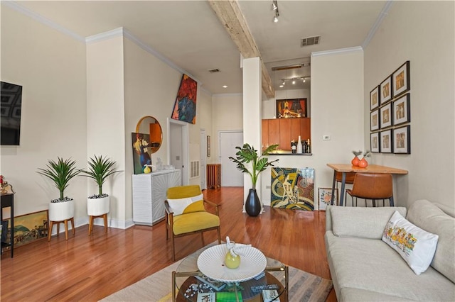 living room with visible vents, ornamental molding, and wood finished floors