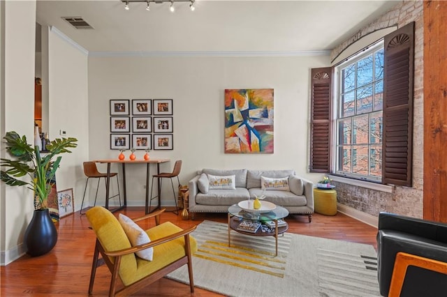 living area featuring visible vents, ornamental molding, track lighting, wood finished floors, and baseboards