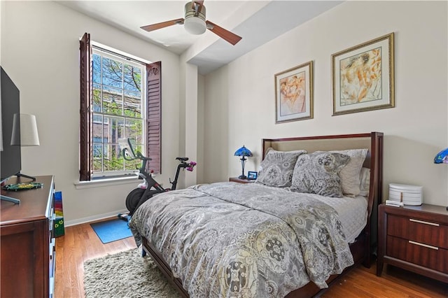 bedroom featuring ceiling fan, baseboards, and wood finished floors