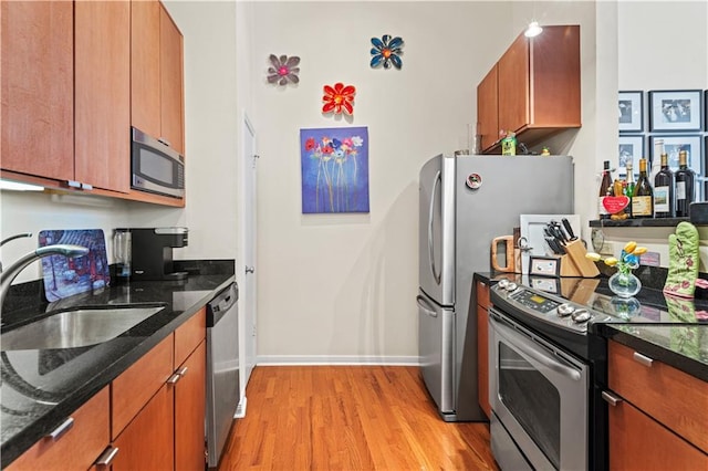 kitchen with dark stone counters, light wood-style flooring, brown cabinets, and stainless steel appliances