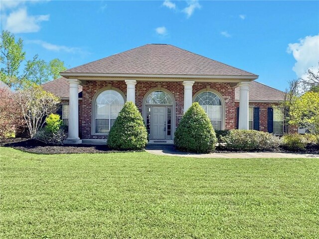 greek revival inspired property with a front yard, brick siding, and roof with shingles