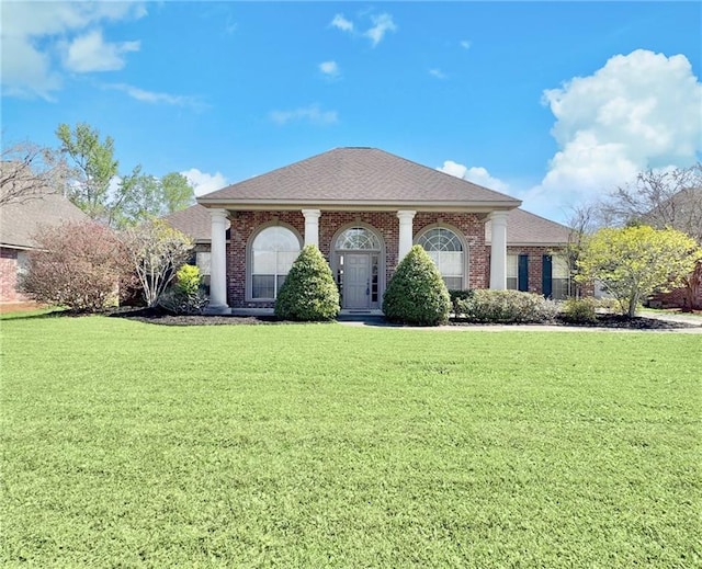 greek revival house with a front yard, brick siding, and roof with shingles