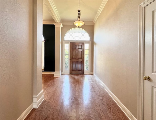 foyer entrance with a textured wall, wood finished floors, baseboards, and ornamental molding