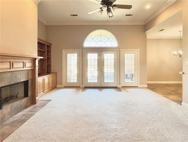 living room featuring light carpet, ceiling fan with notable chandelier, a tile fireplace, and baseboards