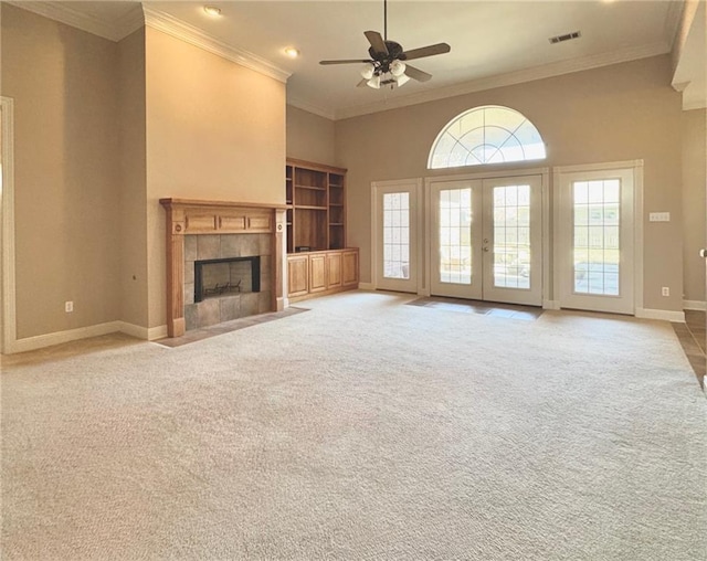 unfurnished living room featuring visible vents, baseboards, carpet, a tile fireplace, and a ceiling fan