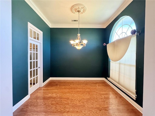 unfurnished dining area with visible vents, crown molding, baseboards, an inviting chandelier, and wood finished floors