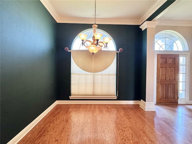 foyer entrance featuring a notable chandelier, plenty of natural light, baseboards, and wood finished floors