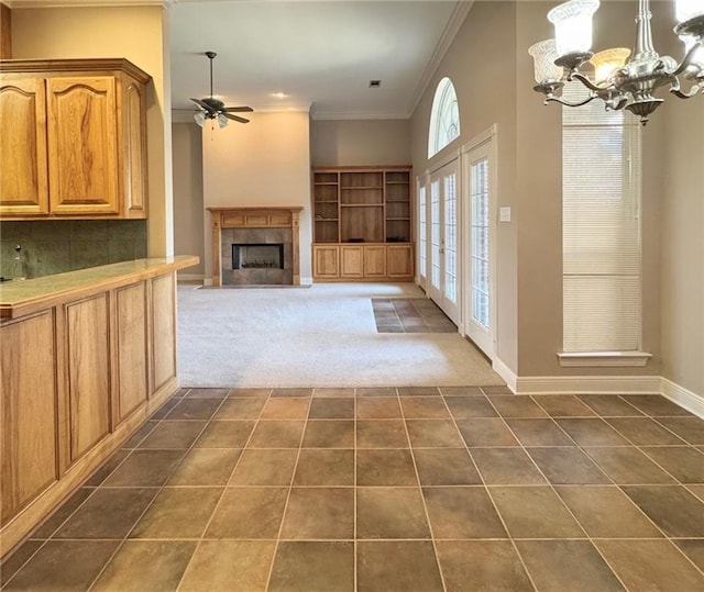 interior space featuring dark tile patterned flooring, ceiling fan with notable chandelier, dark carpet, crown molding, and baseboards