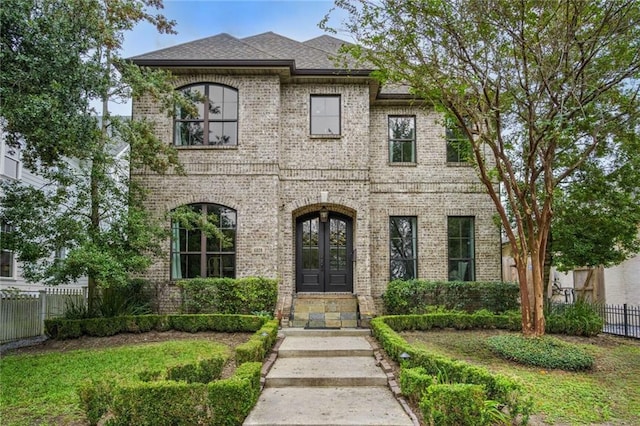 french country inspired facade featuring brick siding, french doors, and fence