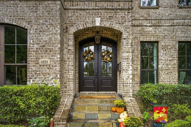 entrance to property featuring french doors and brick siding