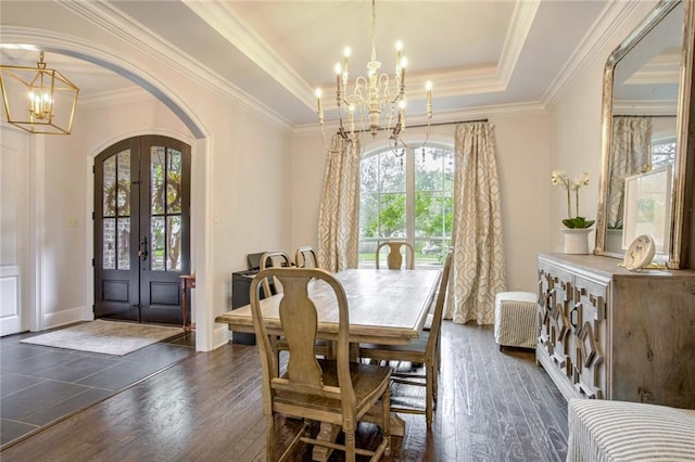 dining space with a chandelier, french doors, arched walkways, a raised ceiling, and dark wood-style flooring