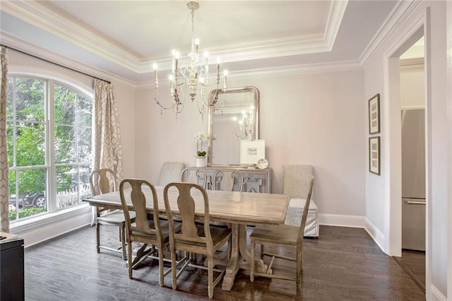 dining room featuring ornamental molding, a tray ceiling, dark wood-style floors, an inviting chandelier, and baseboards