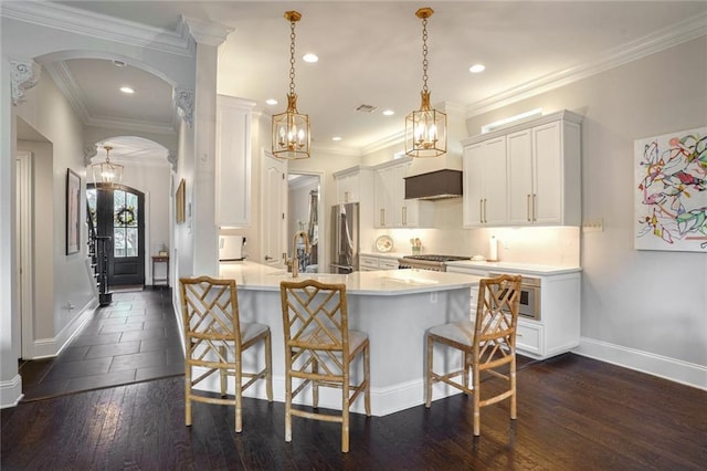 kitchen with arched walkways, a peninsula, a breakfast bar, and exhaust hood