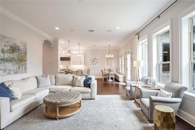 living area with baseboards, a notable chandelier, wood finished floors, and ornamental molding