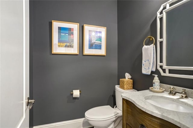 bathroom with toilet, vanity, and baseboards