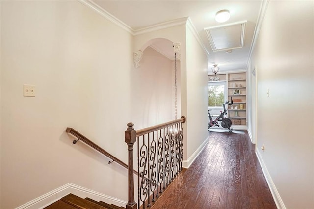 hallway featuring baseboards, attic access, hardwood / wood-style flooring, crown molding, and an upstairs landing