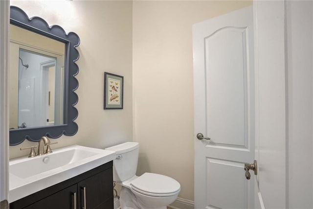 half bath with toilet, vanity, and baseboards