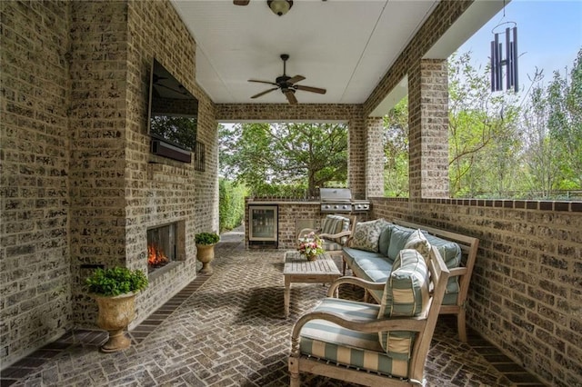 view of patio with an outdoor kitchen, area for grilling, an outdoor living space with a fireplace, ceiling fan, and wine cooler