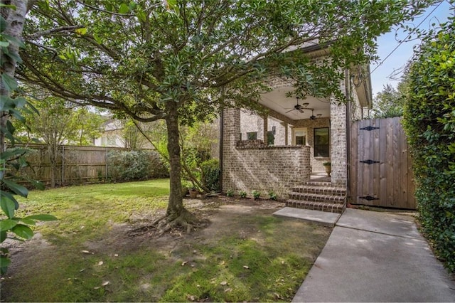 view of yard with a gate, ceiling fan, and fence