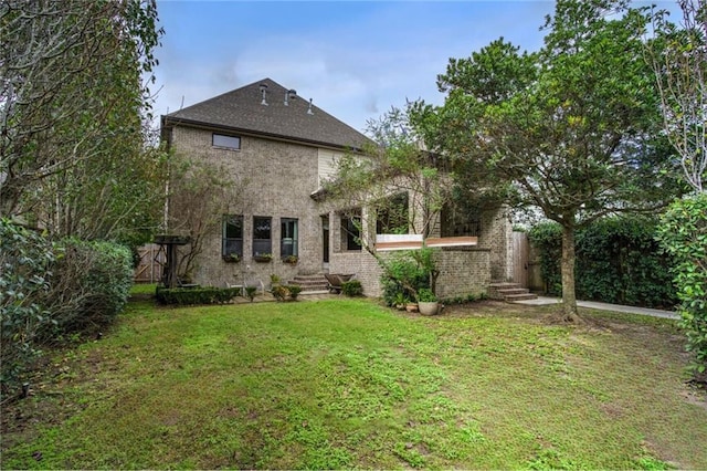 back of property featuring a yard and brick siding