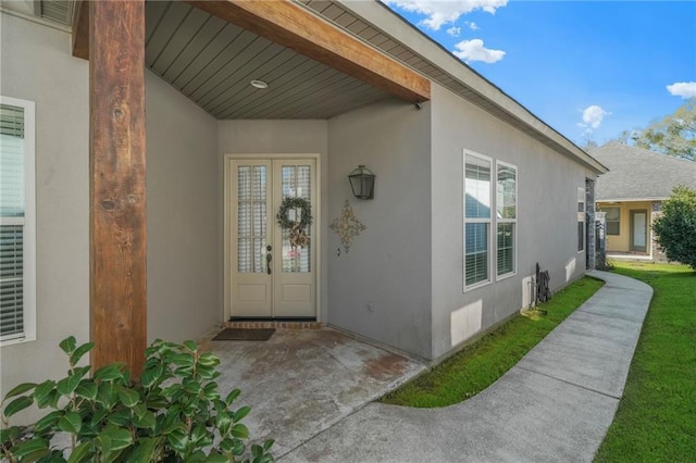 view of exterior entry with french doors, visible vents, and stucco siding