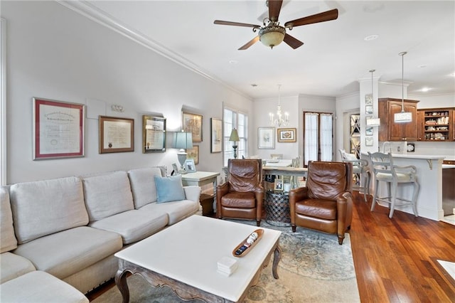 living room featuring wood finished floors, crown molding, and ceiling fan with notable chandelier