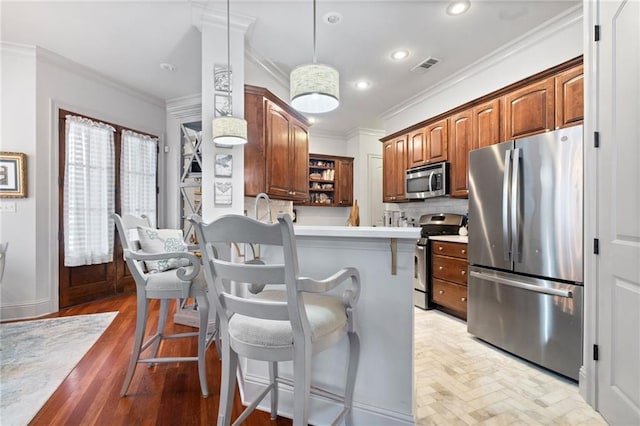 kitchen featuring a breakfast bar, visible vents, stainless steel appliances, and ornamental molding