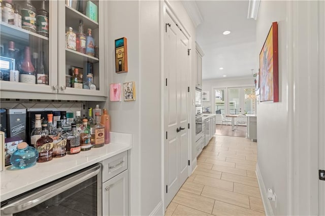 bar with wine cooler, a dry bar, ornamental molding, stainless steel oven, and recessed lighting