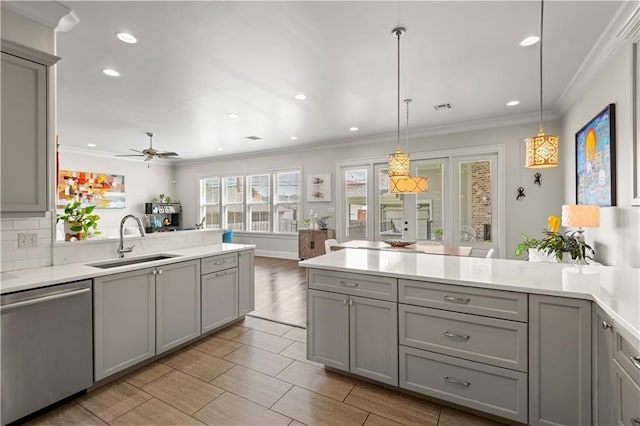 kitchen featuring dishwasher, a peninsula, gray cabinetry, and a sink