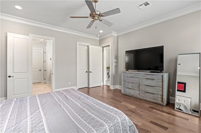 bedroom with visible vents, ornamental molding, baseboards, and wood finished floors