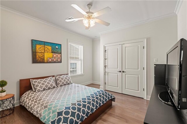 bedroom featuring visible vents, wood finished floors, a closet, crown molding, and baseboards