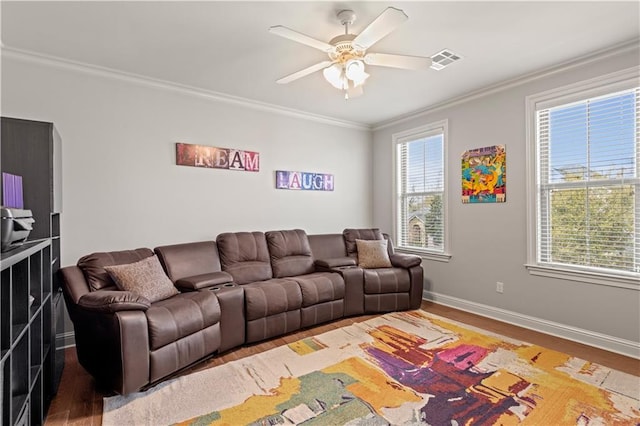 living room with crown molding, visible vents, a wealth of natural light, and ceiling fan