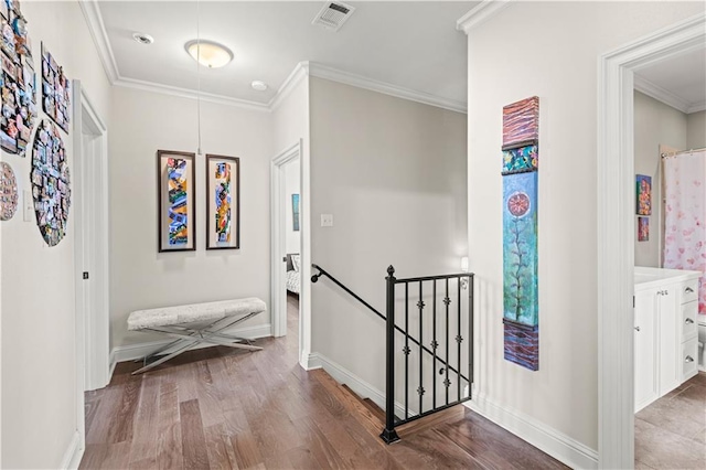 hall with visible vents, crown molding, baseboards, an upstairs landing, and wood finished floors