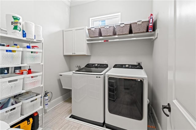 clothes washing area with cabinet space, light wood-style flooring, separate washer and dryer, and baseboards