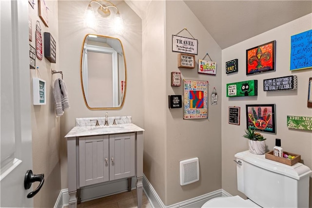 bathroom featuring toilet, vanity, baseboards, and vaulted ceiling