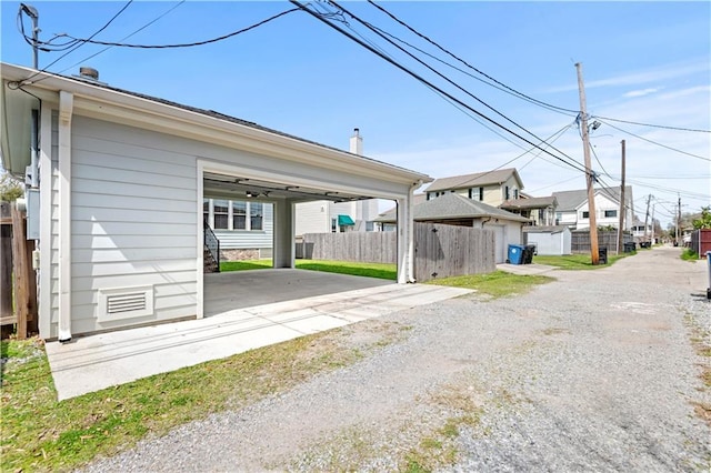 exterior space featuring a residential view, an attached carport, gravel driveway, and fence